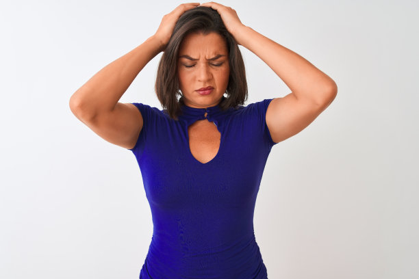 年轻女子穿着蓝色T恤，白色背景，头痛欲裂，双手抱头图片下载