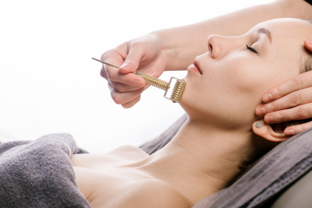 在美容院刮痧脸部按摩时，滑脸轮紧贴下巴。图片下载