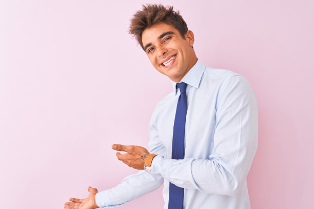 年轻英俊的商人穿着衬衫和领带站在孤立的粉红色背景邀请进入自然微笑和张开手图片下载