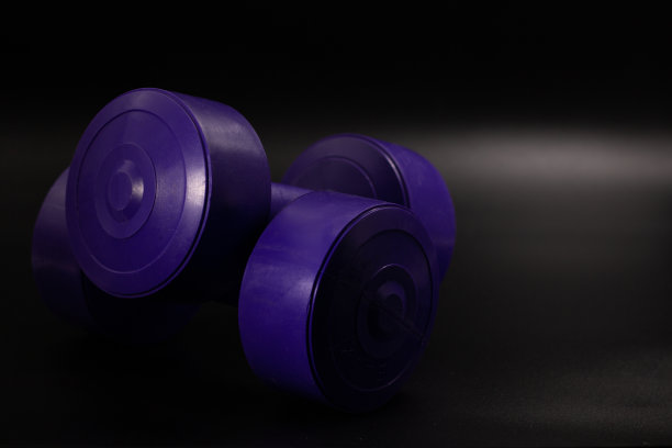 两个紫色哑铃，一个接一个，背景是黑色的图片下载