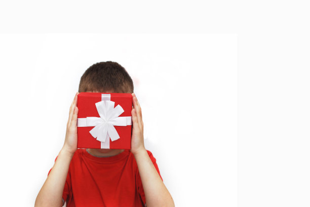 一个年轻男人在白色背景上拿着一个红色的礼品盒，孩子用盒子遮住脸图片下载