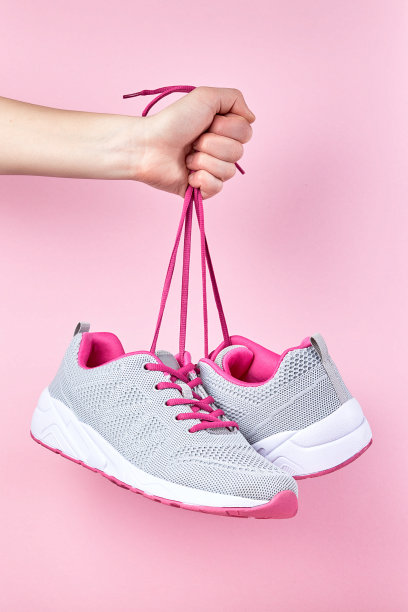 粉红色背景的跑步运动鞋，一双时尚时尚的运动鞋在手图片下载