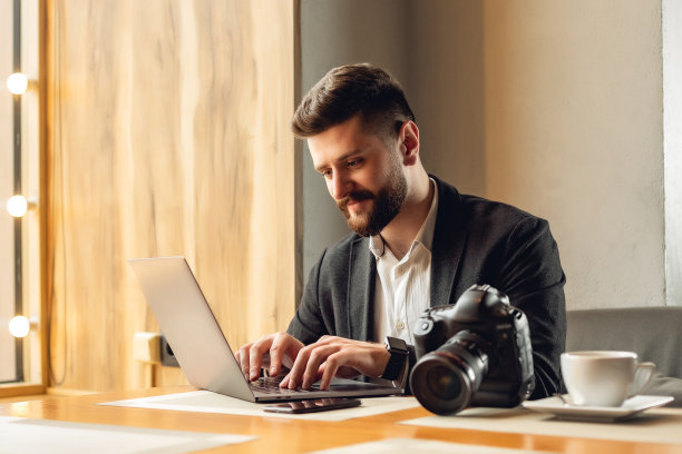 有胡子的帅哥在咖啡厅里。生活方式概念照片与复制空间。图片与笔记本电脑，数码专业相机和咖啡图片下载