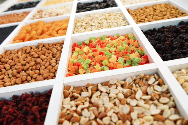 甜的橘子酱方块躺在一个方形的格子里。在邻近的牢房里，填上坚果，花生，开心果图片下载