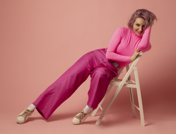 一个穿着粉红色裙子的女人正坐在一张椅子上，前面是粉红色的背景图片下载