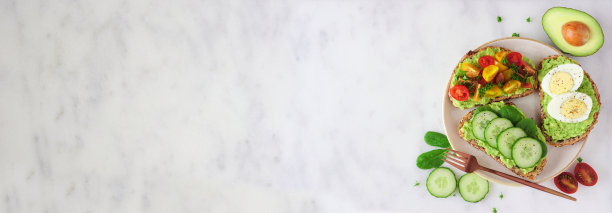 横幅上放着一盘健康的鳄梨吐司，边沿是白色大理石背景图片下载