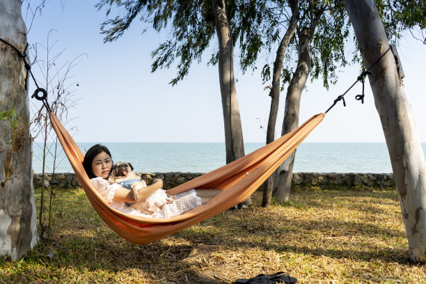 有趣可爱的哈巴狗微笑着伸出舌头，与她的主人，快乐的年轻的家庭，躺在沙滩上舒适的吊床上休息的女人的旅行。幸福时光的概念。图片下载