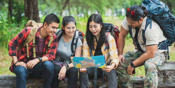 和朋友在森林里徒步旅行。穿过乡村，看地图。徒步旅行者看地图。团队户外活动。徒步旅行。露营和野生动物的概念。图片下载