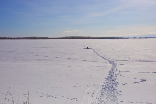 一个孤独的渔民在一条结冰的大河上。图片下载