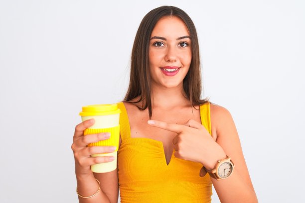 年轻美丽的女孩喝着纸杯带走的咖啡在孤立的白色背景很幸福的手指和手指图片下载