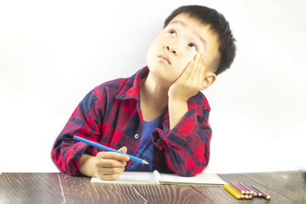 一个小男孩坐在书桌前做作业图片下载