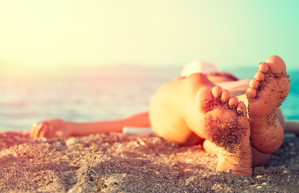 女人的脚踩在海边的白沙上。图片下载