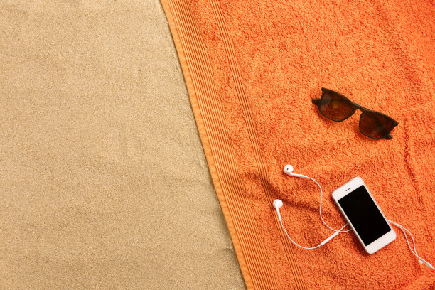 沙滩毛巾，耳机，沙滩背景。最小的海滩概念。俯视图和拷贝空间。图片下载