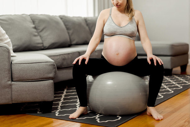 孕妇在瑜伽球上跳跃图片下载