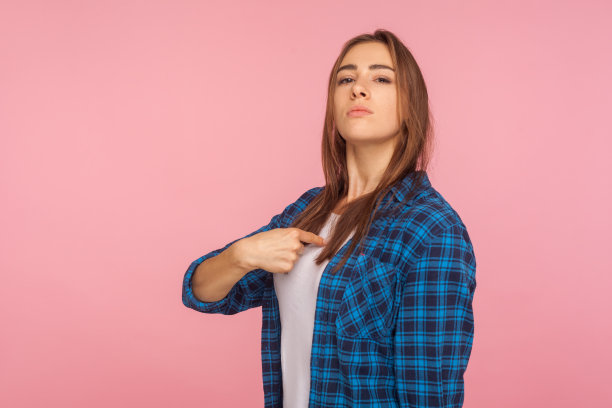 这是我!一个骄傲自信的女孩穿着格子衬衫指着自己，看起来很傲慢图片下载