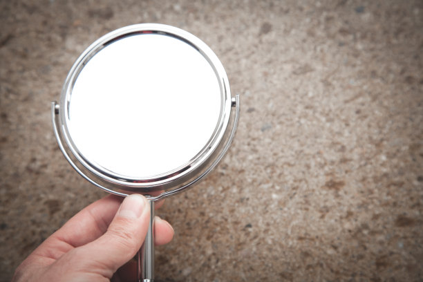 棕色背景上的男性手握镜子。图片下载