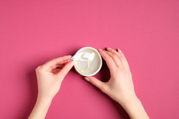 容器里的眼罩，俯视图。女性手握罐与眼霜下垫。胶原眼膜保湿，眼袋下的治疗理念。图片下载