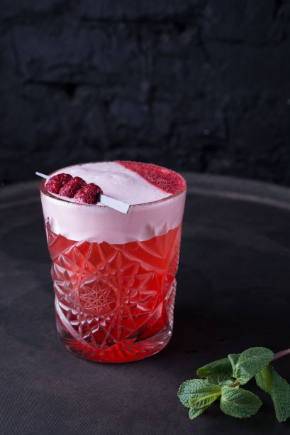 为派对准备的红色鸡尾酒的宣传照片。带有绿色的薄荷小枝和装饰性的覆盆子。在黑暗的背景上。以乡村风格。酒精图片下载