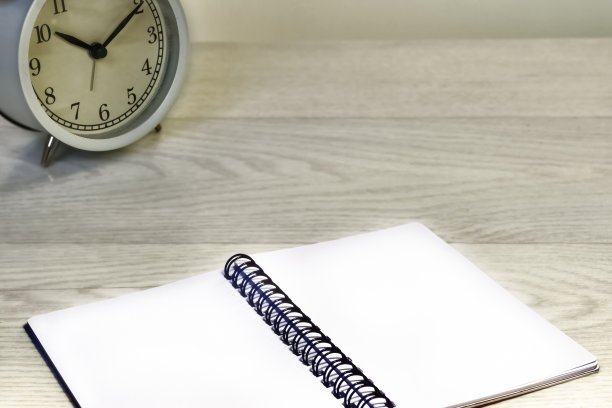 业务。工作场所。闹钟和记事本放在一张木桌上图片下载