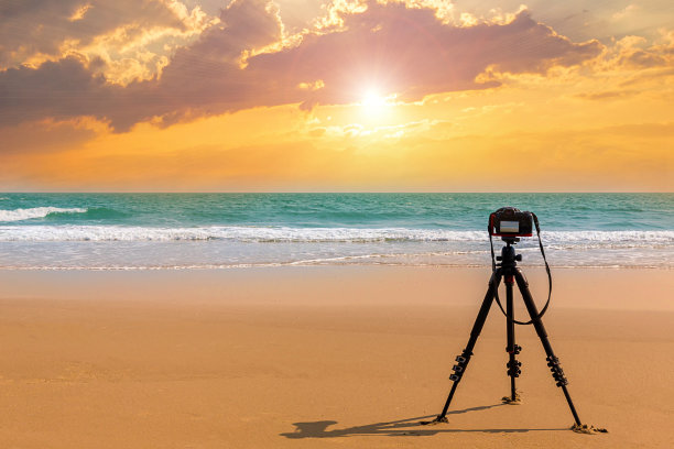 数码专业相机站在三脚架上拍摄大海。黄昏的天空背景。缤纷的晚霞天空和云。在黄昏时间背景中生动的天空。火红的夕阳天空。美丽的图片下载