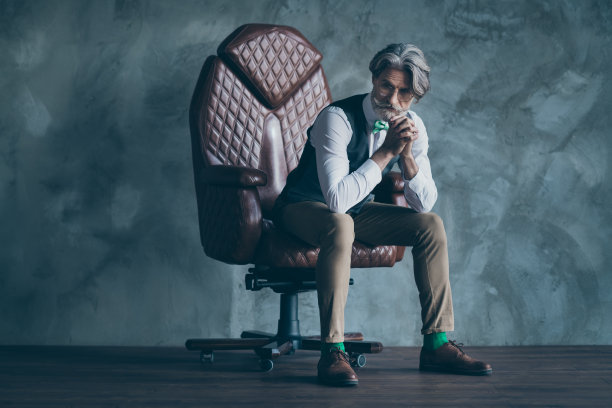 严肃沉思的梦幻老人的全长照片坐在扶手椅上看拷贝空间梦穿点白色背心，领结孤立在灰色背景图片下载