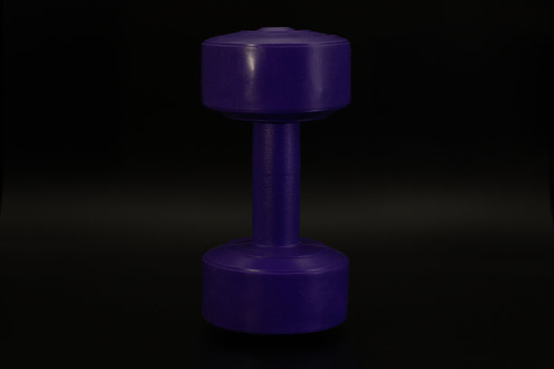 水平图像的紫色哑铃垂直定位在一个黑暗的背景图片下载