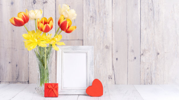 郁金香花在玻璃花瓶与画框装饰在木桌背景墙在家里，近。图片下载