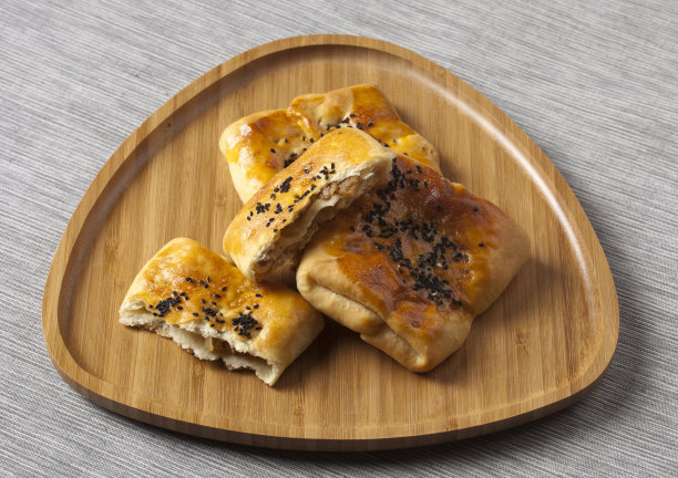 木盘上刚烤好的自制小圆面包。水平特写白色背景。图片下载