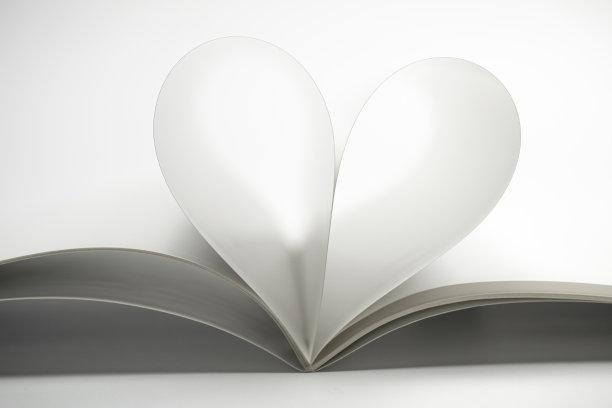 两个空白的杂志页变成一个心形。干净的正面照片的杂志上的白色背景，作为概念情人节，爱情故事等。图片下载