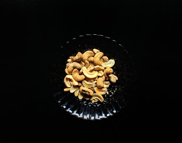 一盘腰果，背景为黑色。健康食品的概念图片下载