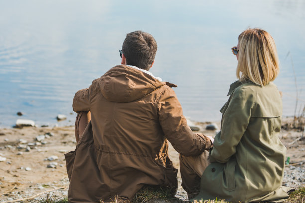 一家人在水边散步。坐在海滩上。小孩往水里扔石头图片下载