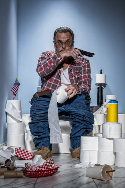 消化不良的男子坐在马桶上，用手枪守卫着他的卫生纸图片下载