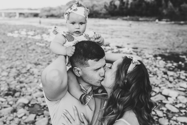 父亲在湖边沙滩上肩扛女儿，享受夏日亲子时光。黑白照片，夫妻亲吻图片下载