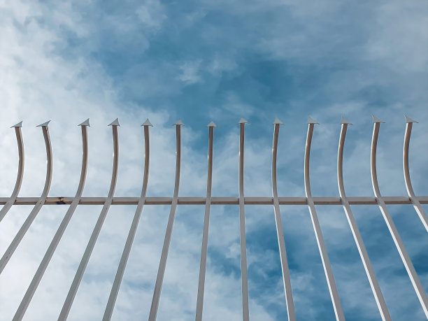 铁艺栅栏隔离在蓝天和云的背景与复制空间。图片下载