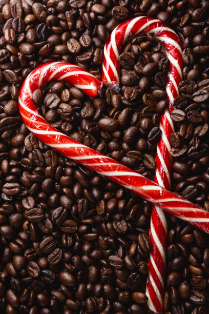 烘焙咖啡豆的背景。一颗圣诞手杖做成的心。甜的棒棒糖图片下载