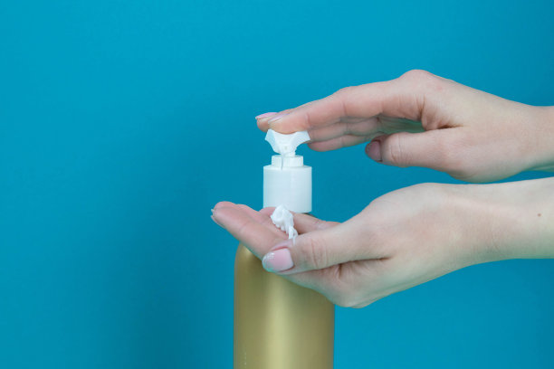 女人的手在手上涂肥皂。蓝色背景下的手部消毒概念图片下载