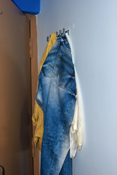 旧牛仔长裤挂在墙上。素材图片
