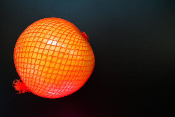 柚子在一个包装网在一个黑色的背景。图片下载