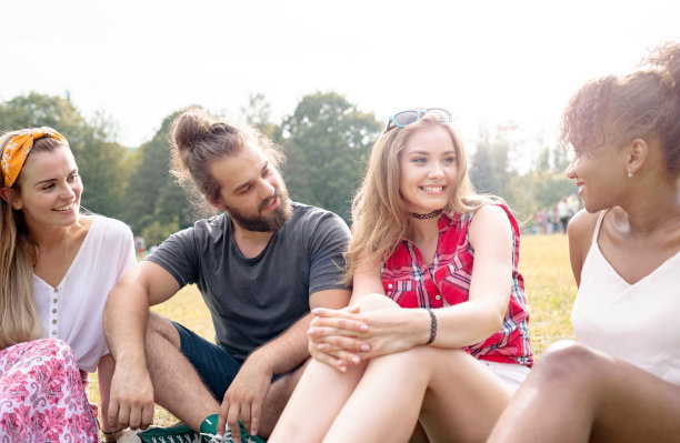 在夏季音乐节上，一群朋友坐在草地上图片下载