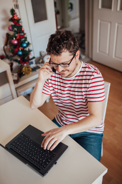 年轻男人在家中办公室打电话（库存照片）图片下载