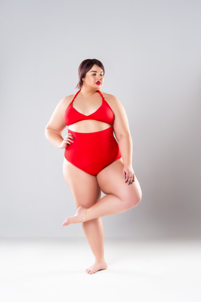 穿红色泳衣的加大码时装模特，灰色背景下的胖女人内衣秀图片下载