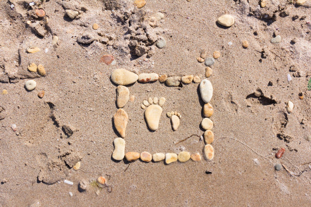 令人感动的照片上的沙滩上的海卵石。这是一个孩子和大人用石头做成的脚。海水中的浮沙。卡。背景。图片下载