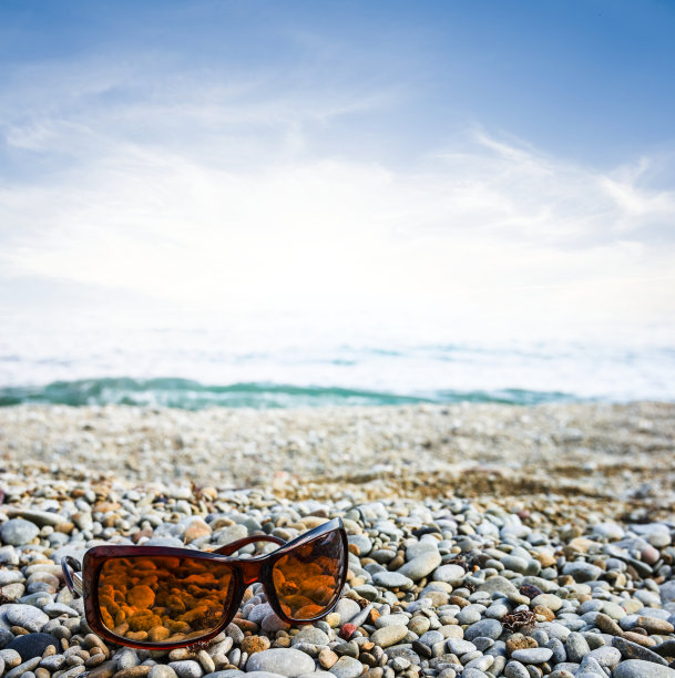 太阳镜躺在多岩石的海岸上图片下载