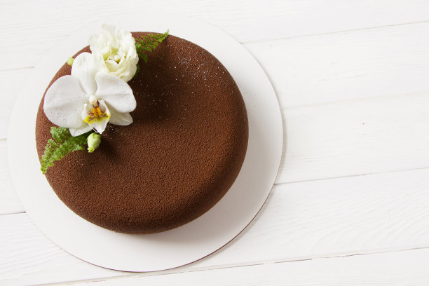 时髦的慕斯蛋糕覆盖了巧克力天鹅绒装饰的白色花朵。白色背景，空白。婚礼概念，圣瓦伦丁节，母亲节，生日蛋糕。布朗蛋糕图片下载