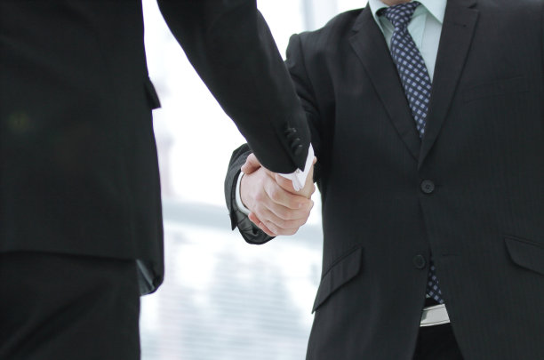 两个穿着商务套装的企业家握手的特写图片下载