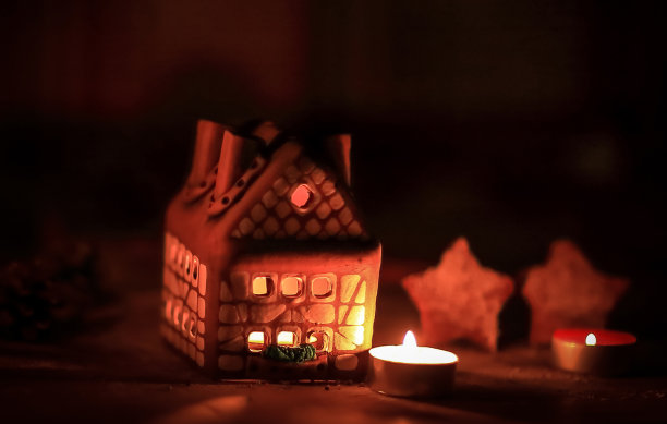 姜饼屋蜡烛在模糊的背景下的桌子。图片下载