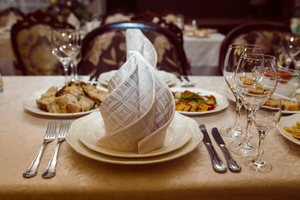 餐厅里的婚宴餐桌上有餐具、餐巾、陶器和白色桌布。图片下载
