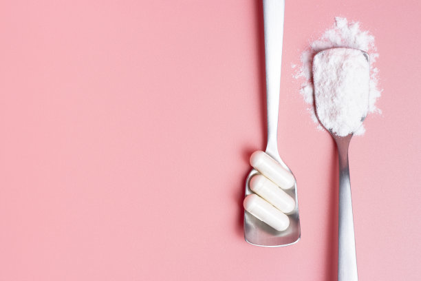 胶囊和胶原蛋白粉汤匙在粉红色的背景，复制空间。图片下载