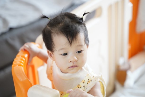 可爱的8个月大女婴站立在家中儿童隔断背景前观看某物竖版照片图片下载