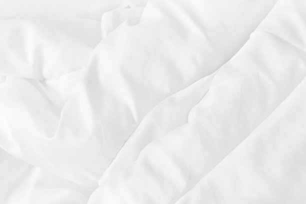 特写俯视图的白色床单和皱纹凌乱的毯子在卧室早上醒来后。图片下载